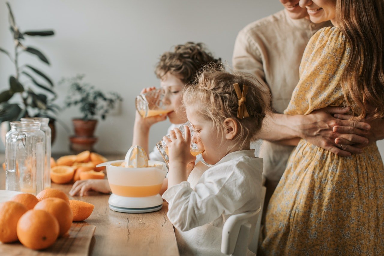 A Girl and Boy Drinking Orange Juice